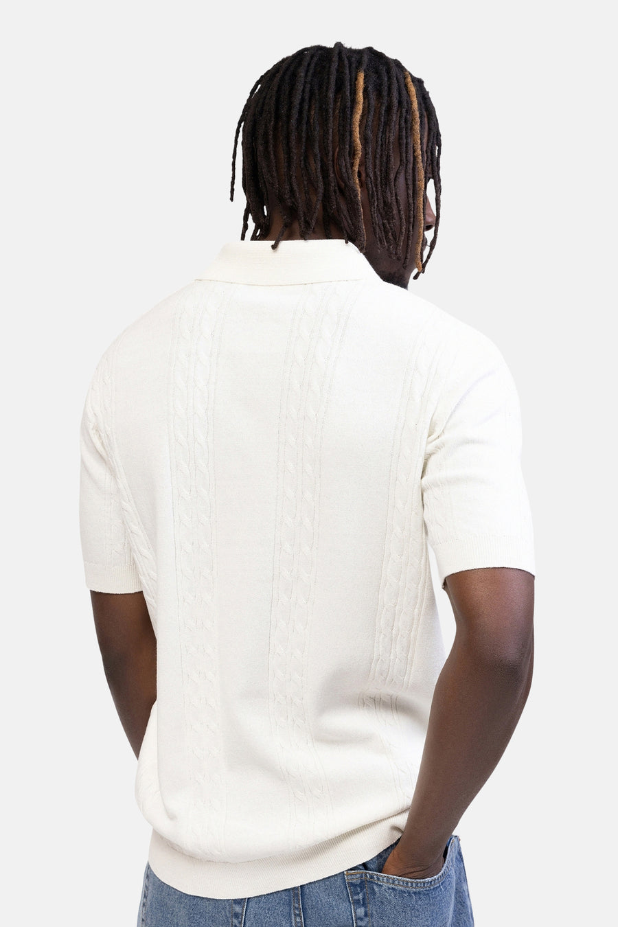 Ecru polo van REDEFINED REBEL, gebreid met kabelpatroon, korte mouwen, achterkant op een persoon met jeans.