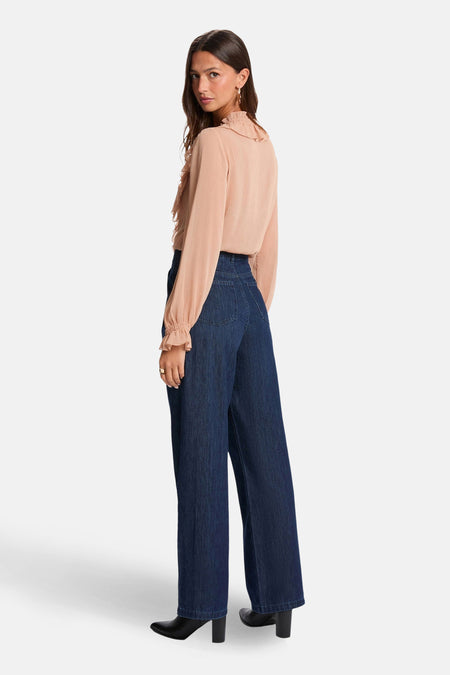 Beige blouse met lange mouwen van Morgan De Toi, met ruches op de hals en gedragen met donkere jeans.
