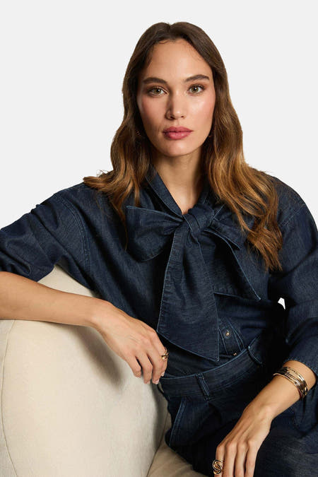 Donkerblauw denim overhemd met lange mouwen van Morgan De Toi, met strikdetail en gouden sieraden.
