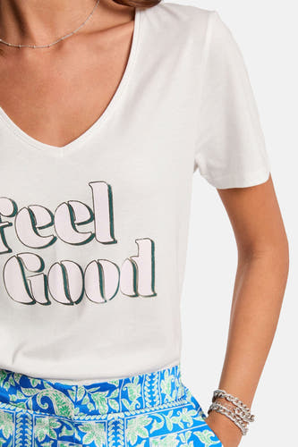 T-shirt blanc à manches courtes de Morgan de Toi, avec le texte "feel good" et porté avec un pantalon bleu imprimé.