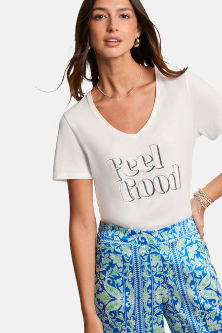 Wit T-shirt met korte mouwen van Morgan De Toi, met de tekst "Feel Good" en een blauwe broek met paisley motief.
