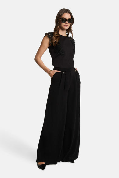 T-shirt noir à manches courtes de Morgan De Toi, fini avec des détails bordés sur les épaules, associé à un pantalon noir à larges pinces et à un chapeau de soleil.