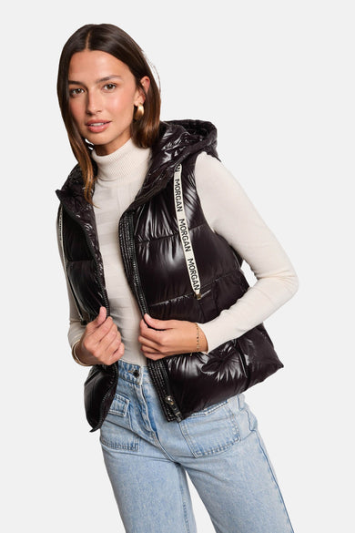 Body sans manches noir de Morgan De Toi, avec capuche et détails de logo verticaux, combiné avec un col roulé blanc et un jean bleu.