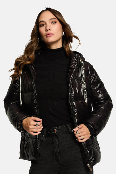 Manteau court noir de Morgan de Toi, avec fermeture éclair et capuche, porté sur un gilet noir et un jean noir.