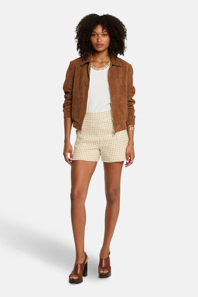 Bruine korte jas van Morgan De Toi, met een gladde textuur, gedragen over een wit topje en tweed shorts.