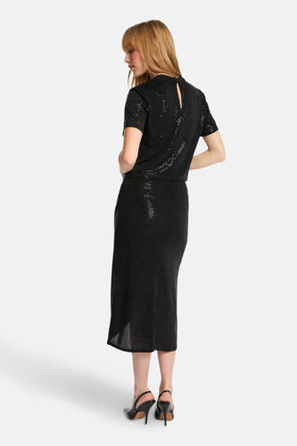 Zwarte rok van Morgan De Toi, met glitterpatroon, midi-lengte en hoge hakken.