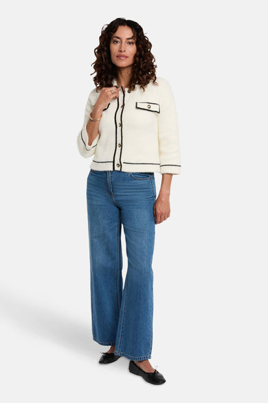Gilet blanc de Morgan De Toi, avec finition noire, porté avec un jeans large et des ballerines noires.