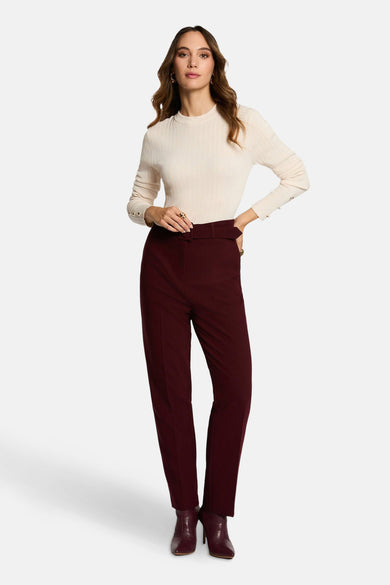 Bordeaux broek van Morgan De Toi, met hoge taille en riem, gecombineerd met een crèmekleurige top en enkellaarsjes.