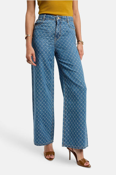 Blauw denim broek van Morgan De Toi, met een all-over monogrampatroon en gedragen met bruine muiltjes.
