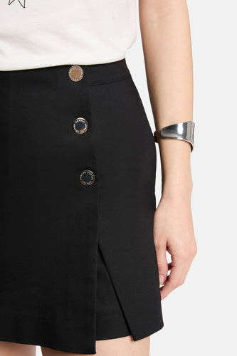 Zwarte rok met knopen en zilveren armband.
