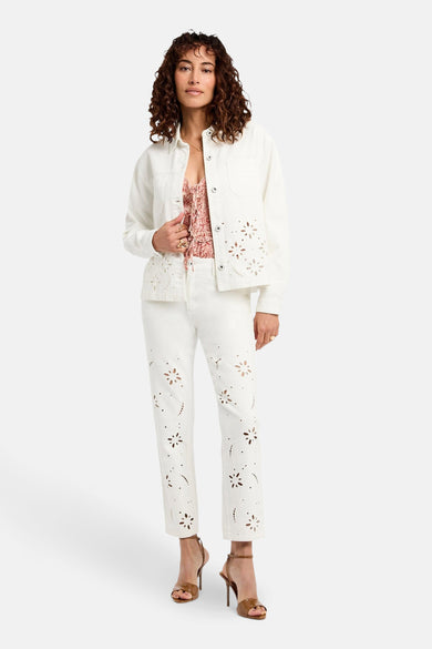 Chemise blanche à longues manches de Morgan De Toi, portée avec un haut rose et un short blanc à motifs floraux.