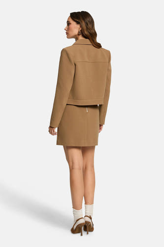 Beige korte jas van Morgan De Toi, compleet met bijpassende rok en bruine hakken.
