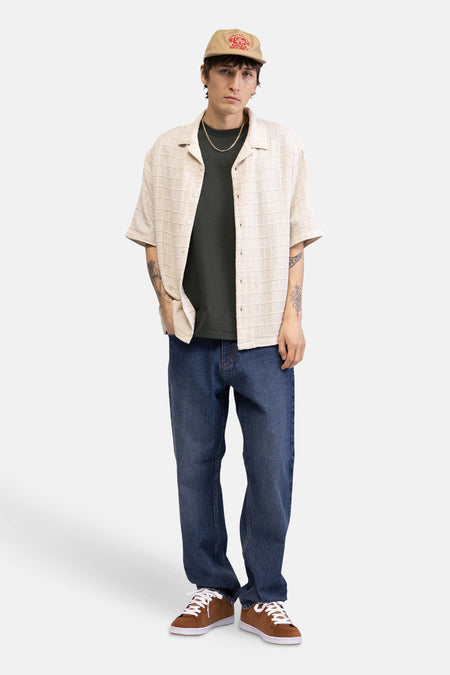 Beige overhemd met korte mouwen van REDEFINED REBEL, met geweven gestreepte textuur, gedragen over een donkergroen T-shirt.