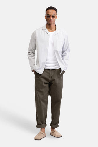 Chemise blanche à rayures à manches longues de REDEFINED REBEL, portée sur un t-shirt blanc, un pantalon marron et des sabots beiges.