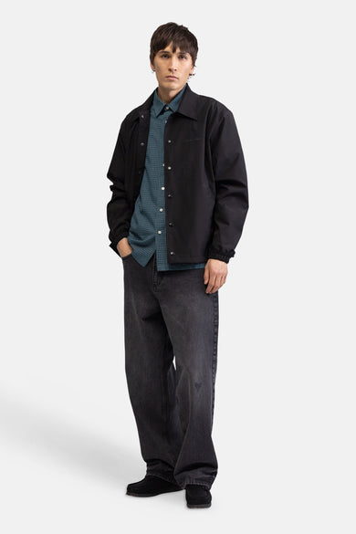 Chemise à manches courtes à carreaux verts de REDEFINED REBEL, avec de petits carreaux, portée sous une veste noire.