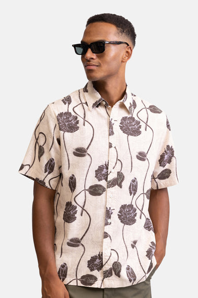 Multicolor korte mouwen overhemd van REDEFINED REBEL met donkere bloemenprint op crèmekleurige stof, gedragen door model met zonnebril, front view