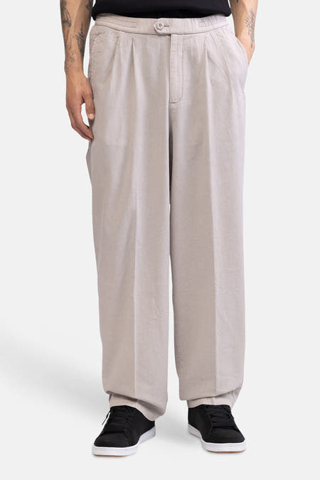 Ecru broek van REDEFINED REBEL met wijde pasvorm, plooien, knoopsluiting en gestyled met een zwart T-shirt en sneakers.