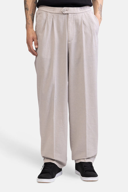Ecru broek van REDEFINED REBEL met wijde pasvorm, plooien, knoopsluiting en gestyled met een zwart T-shirt en sneakers.