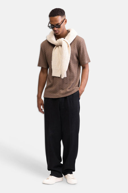 Zwarte broek van REDEFINED REBEL, met subtiele textuur en losse pasvorm, gedragen door een man met een bruin shirt en witte sneakers.