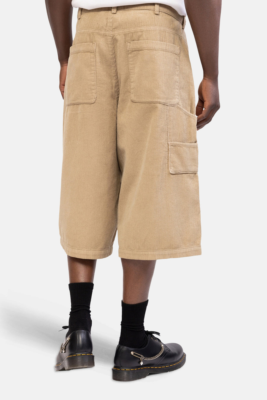 Beige corduroy short van REDEFINED REBEL, van achteren gezien met opgestikte zakken en wijde pijpen, gedragen met zwarte sokken en schoenen.