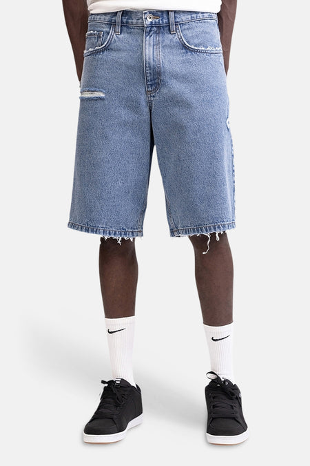 Mid blauwe denim short van REDEFINED REBEL met rafels en gaten, gedragen met witte sokken en zwarte sneakers.