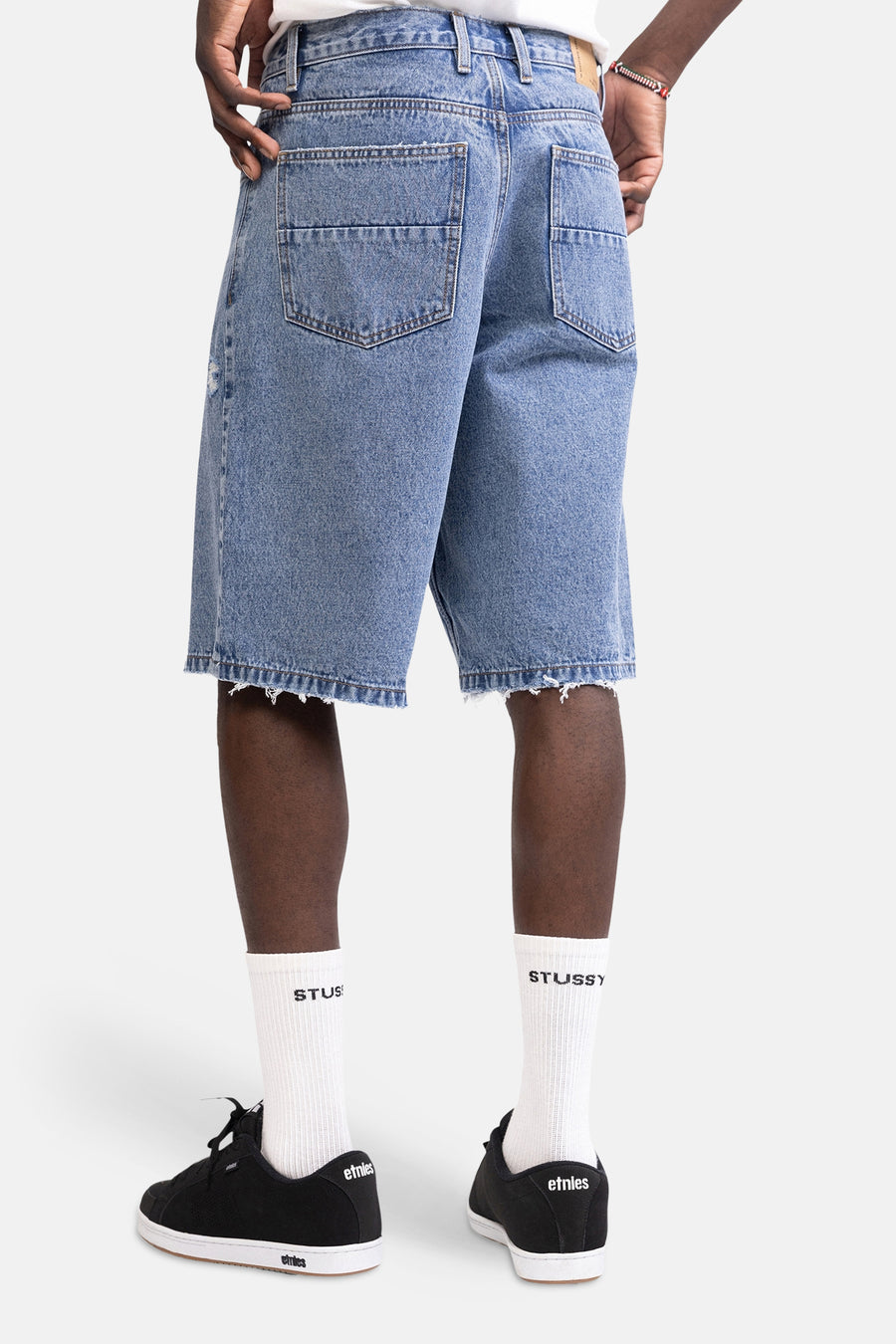 Mid-blauw denim short van REDEFINED REBEL, van achteren gezien met rafelige zomen en twee achterzakken.