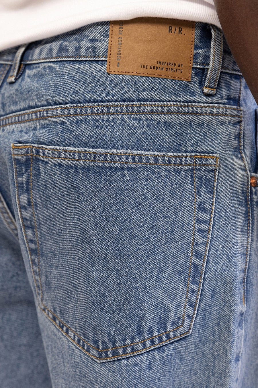 Jean en denim bleu clair coupe large de REDEFINED REBEL, avec une poche arrière et une étiquette de marque en cuir marron.
