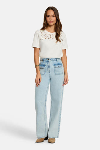 T-shirt blanc à manches courtes de Morgan De Toi, avec perforations décoratives le long de l'encolure, combiné avec un jean bleu clair.