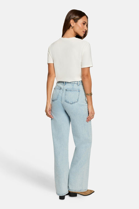Wit T-shirt van Morgan De Toi, gezien van achteren, gecombineerd met wijde, lichtblauwe jeans en suède laarsjes.
