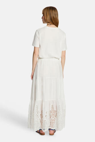 Wit T-shirt van Morgan De Toi, van achteren gezien, gedragen met een lange witte rok met kanten details en blauwe sandalen.