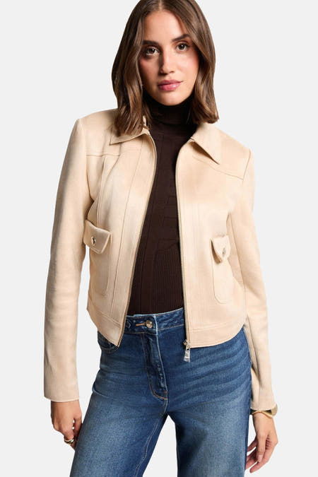 Beige korte jas van Morgan De Toi, met opgestikte zakken en gedragen over een bruine coltrui en blauwe jeans.
