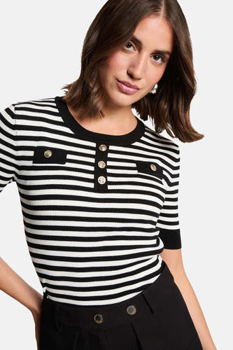 Pull rayé noir et blanc avec col rond de Morgan De Toi, avec des boutons dorés décoratifs et un pantalon noir.