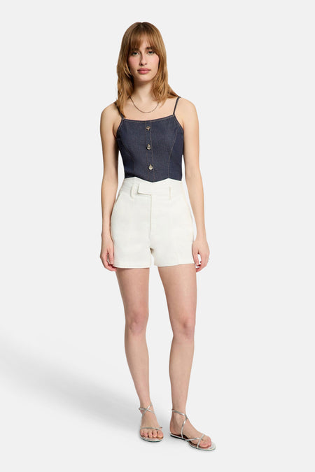 Blazer en denim bleu marine de Morgan De Toi, avec fermeture à boutons, combiné avec un short blanc et des sandales argentées.