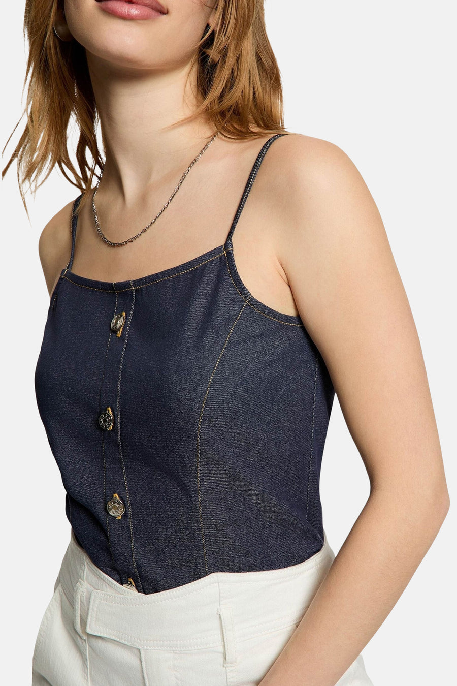 Blazer en denim bleu marine de Morgan De Toi avec fermeture à boutons, coutures et fines bretelles, porté avec un pantalon blanc.