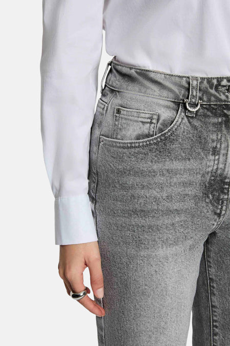 Grijze jeans en wit overhemd.