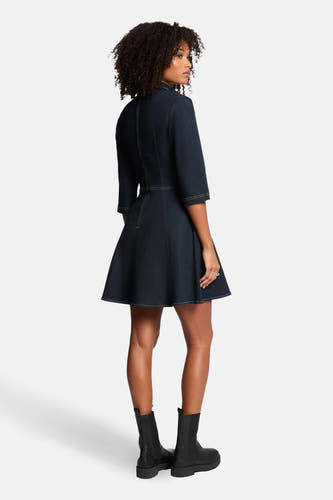 Donkerblauw denim kleedje van Morgan De Toi, met driekwart mouwen en uitlopende rok, gedragen met zwarte laarsjes.

