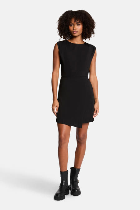 Robe sans manches noire de Morgan De Toi, avec une ceinture élastique et des bottes noires.