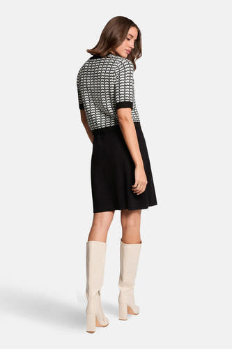 Zwart kleedje met korte mouwen van Morgan De Toi, met een zwart-wit patroon op de bovenkant en crèmekleurige laarzen.
