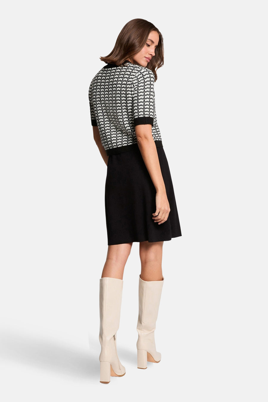 Zwart kleedje met korte mouwen van Morgan De Toi, met een zwart-wit patroon op de bovenkant en crèmekleurige laarzen.
