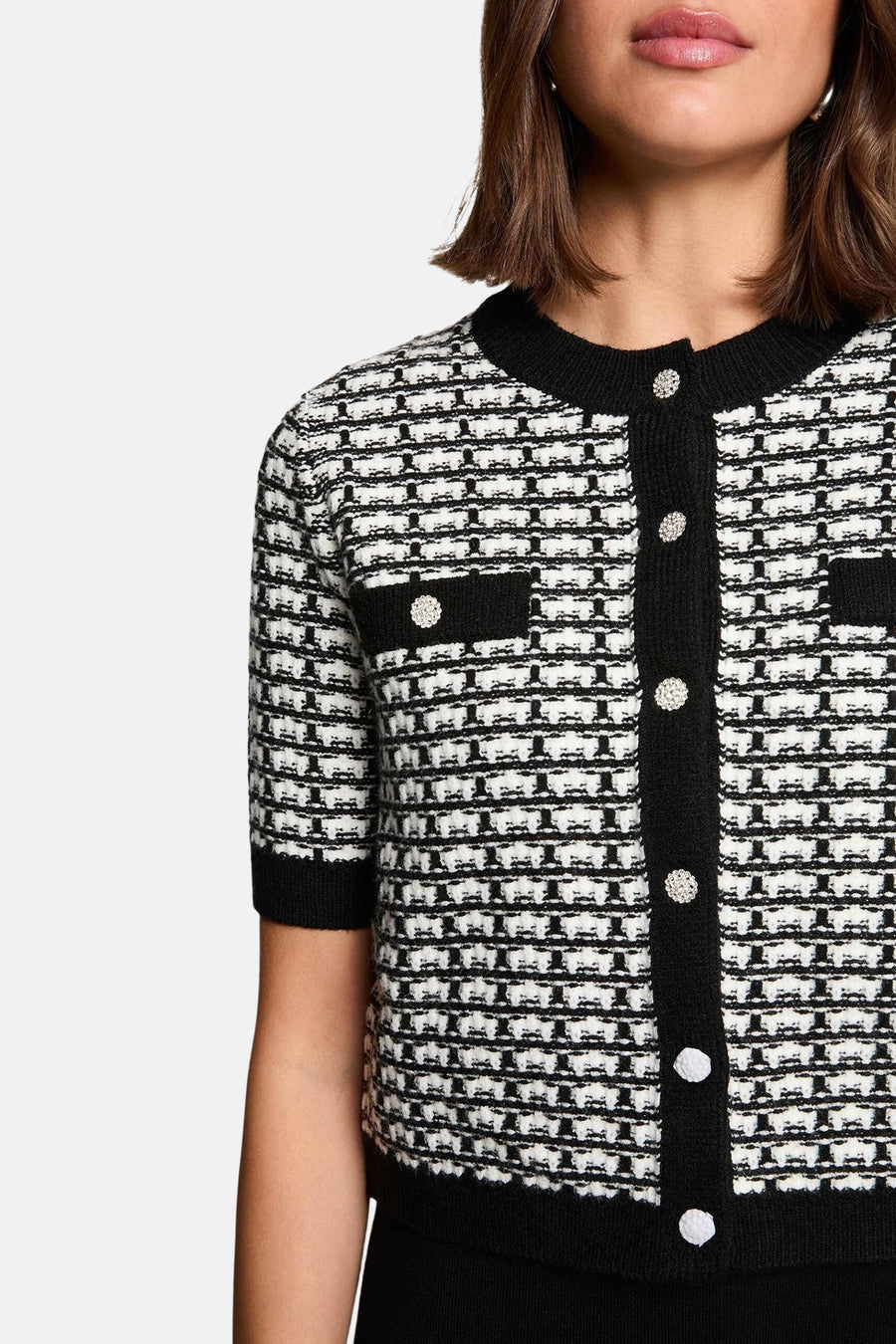 Zwarte jurk met korte mouwen van Morgan De Toi, met decoratieve knopen en een zwart-wit geweven patroon.