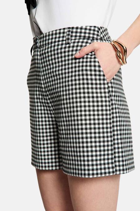 Zwarte short van Morgan De Toi, met een zwart-wit geruit patroon en een hand in de zak.
