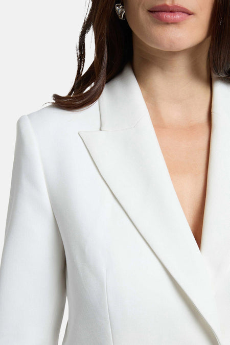 Witte blazer van Morgan De Toi, met zichtbare revers, gedragen door een vrouw met lang haar en een zilveren oorbel.