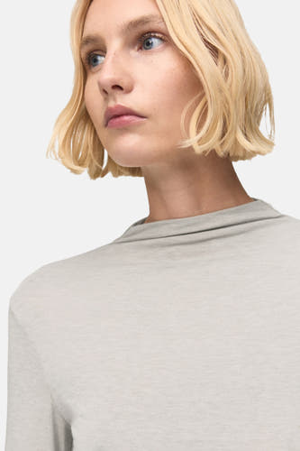 T-shirt beige à longues manches de MANGO, avec un col haut et une style minimaliste.