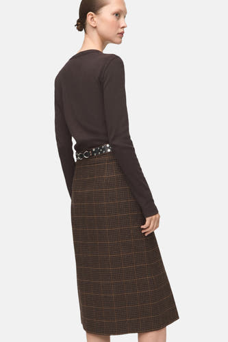 Bruin T-shirt met lange mouwen van MANGO, gecombineerd met geruite rok en riem met zilveren details.