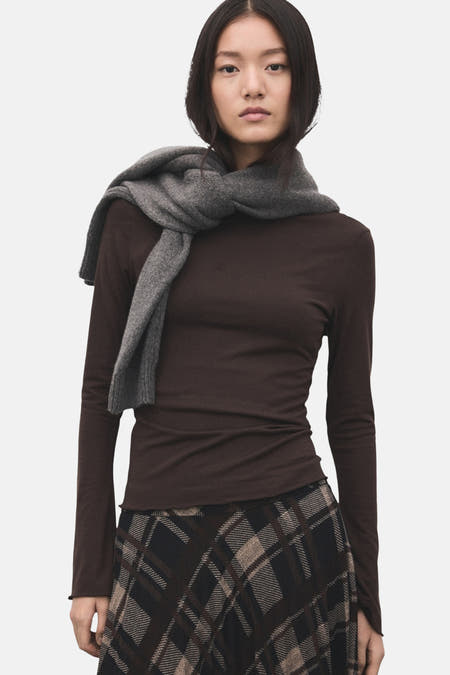 T-shirt marron à manches longues de MANGO, vu par derrière, associé à une jupe longue et des talons noirs.