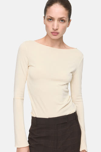 Ecru T-shirt met lange mouwen van MANGO, gecombineerd met een bruine broek met ruitpatroon.