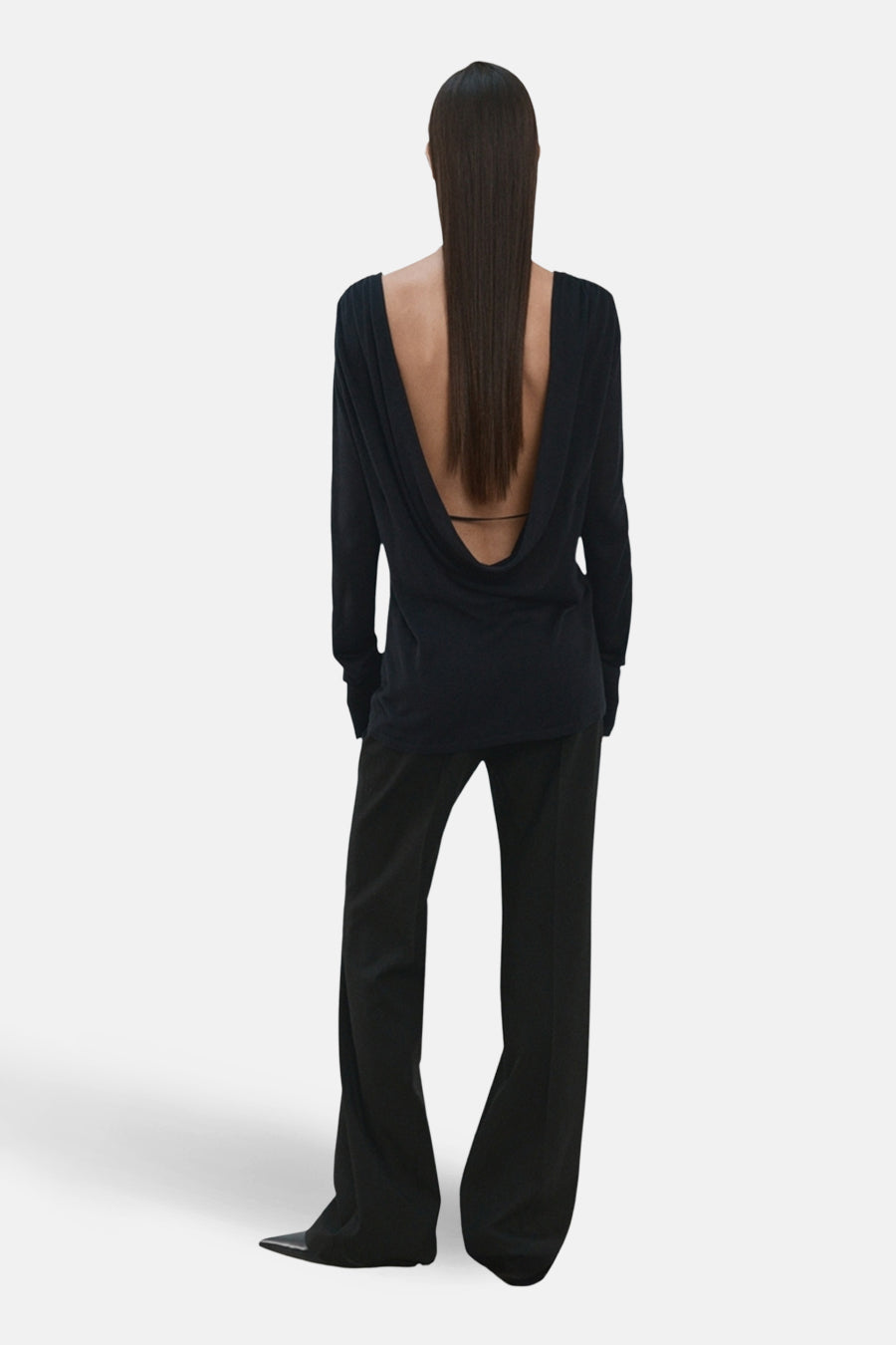 Pull noir à col rond de MANGO, avec un décolleté plongeant dans le dos et des manches longues, combiné avec un pantalon noir.