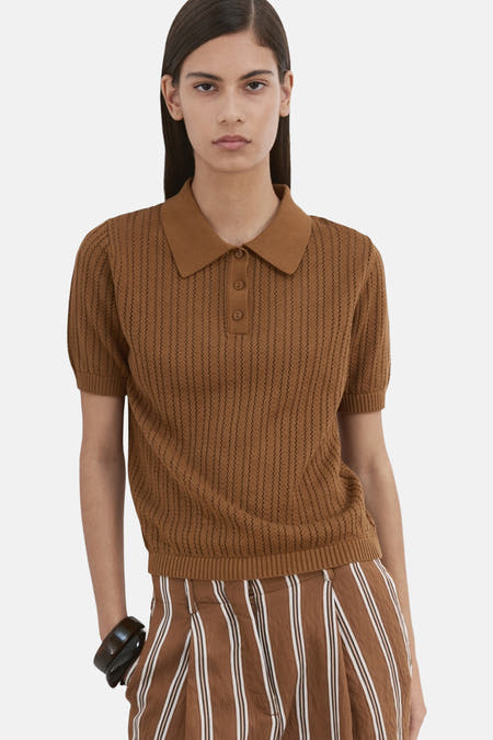 Bruine polo van MANGO met korte mouwen en een verticale streeptextuur, gedragen met gestreepte broek.
