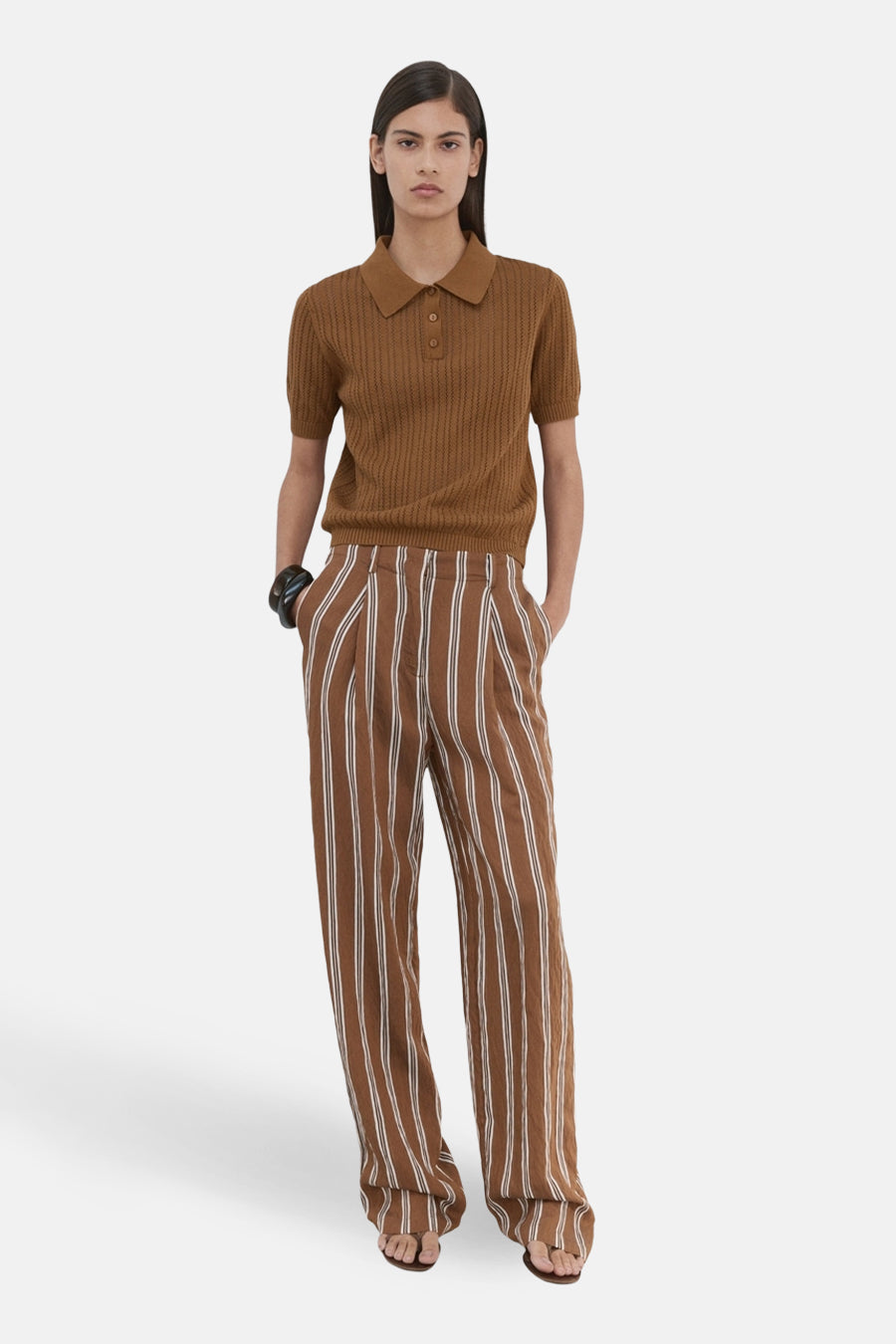 Polo marron de MANGO, à manches courtes et à fines côtes, combinée avec un pantalon large rayé marron.