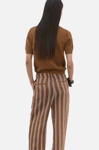 Bruine polo van MANGO, met korte mouwen en een fijn breisel, gecombineerd met een gestreepte broek.
